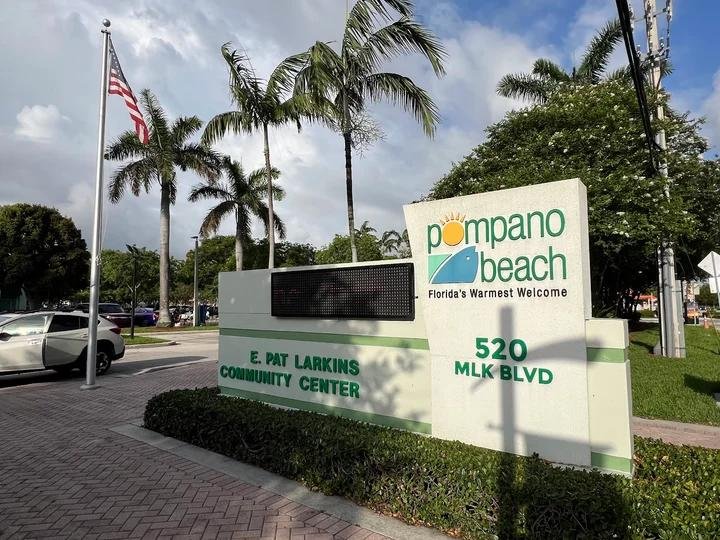 Entrance sign for the E. Pat Larkins Community Center at 520 MLK Boulevard in Pompano Beach, surrounded by palm trees.